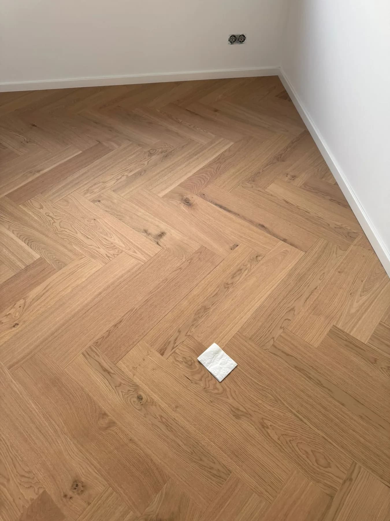 Fischgrätparkett aus Eiche in einem leeren Wohnraum, Blick auf das Verlegemuster