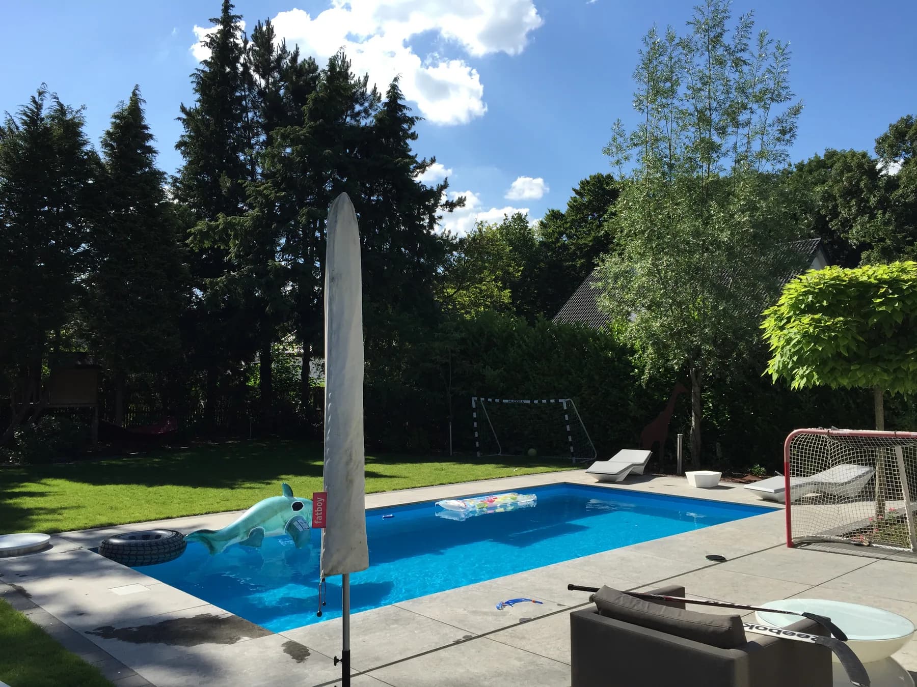 Fertiger Gartenpool mit Blausteinterrasse, Liegen und Sonnenschirm im Grünen