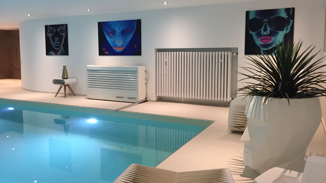 Fertiger Innenpool mit beleuchtetem Wasser, heller Umrandung und Bildern an der Wand