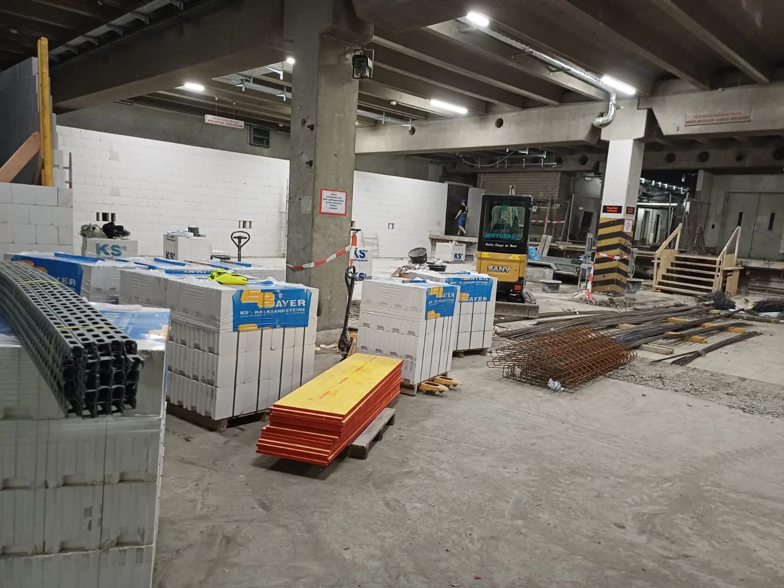 Ladenfläche im Rohbau mit palettierten Kalksandsteinen und Baustelleneinrichtung