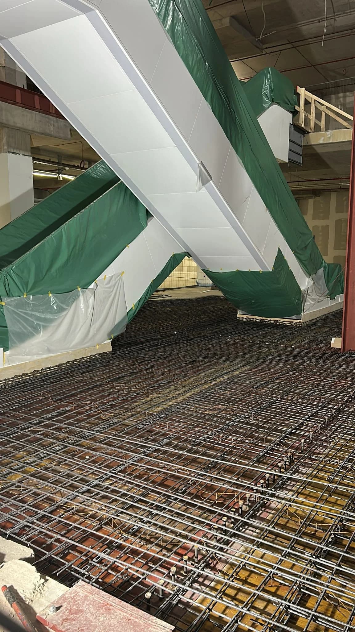Bewehrungslage vor der abgedeckten Rolltreppe, Schutzfolie über den Einbauteilen