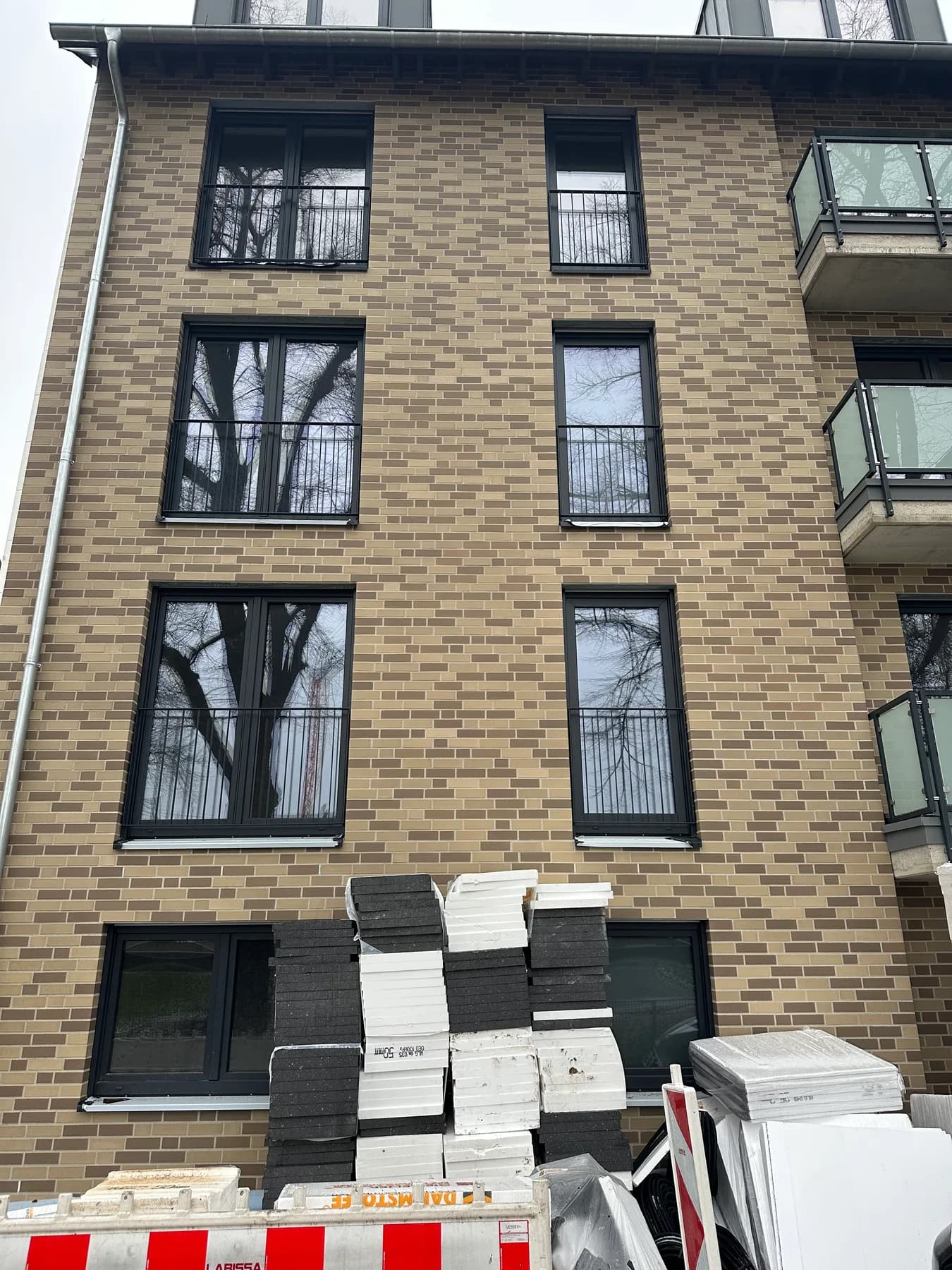 Klinkerfassade aus der Nähe, davor palettierte Baustoffe