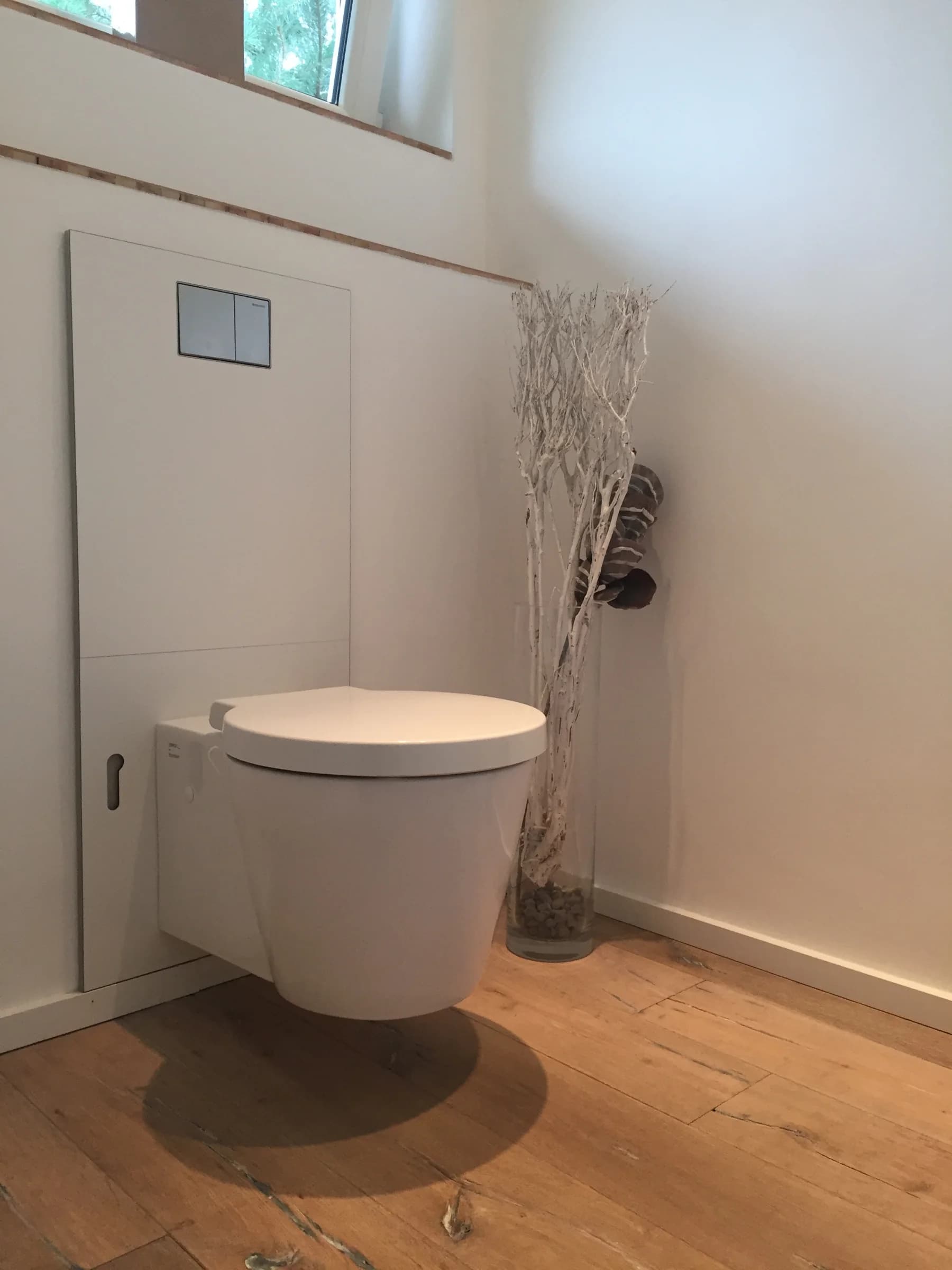 Gäste-WC mit wandhängendem Becken, flächenbündiger Betätigungsplatte und Holzdiele